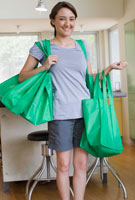 A girl carrying many green bags.