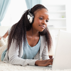 A girl on a laptop wearing headphones.